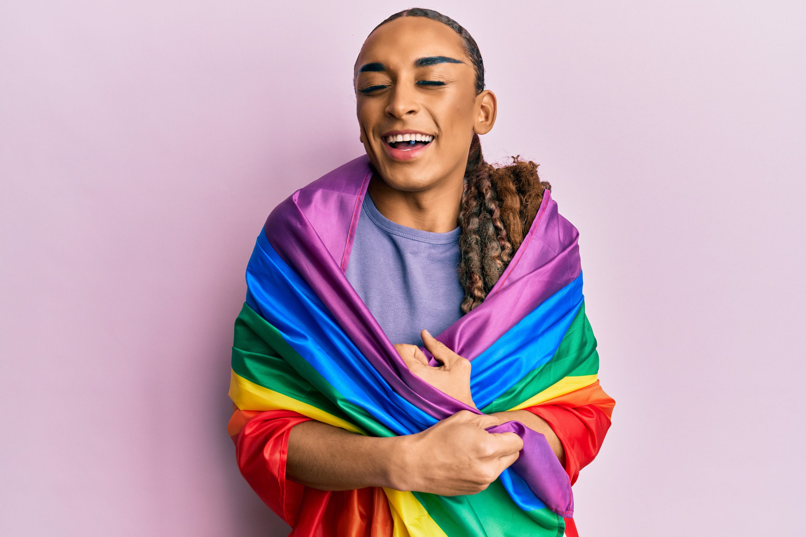 man wearing a pride flag wrapped around him